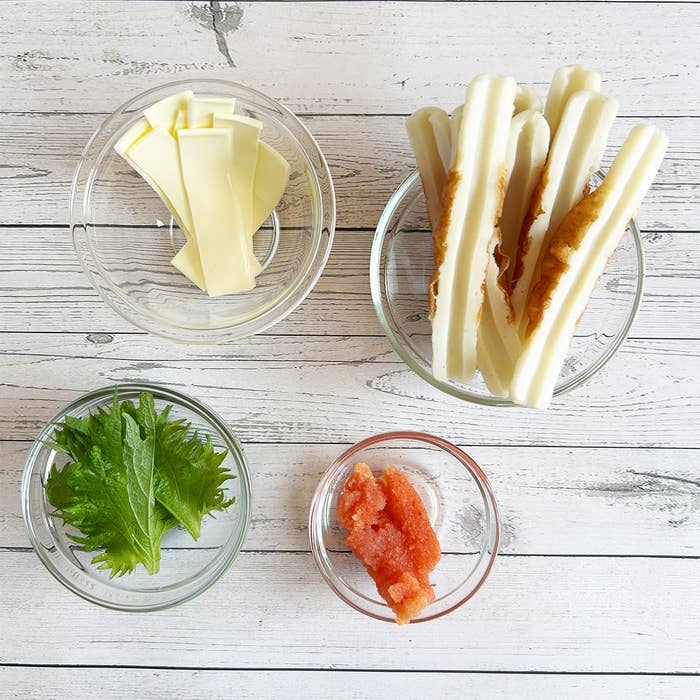 ガラスボウルに並べられた竹輪、チーズ、青じそ、明太子が白い木のテーブルに置かれている。