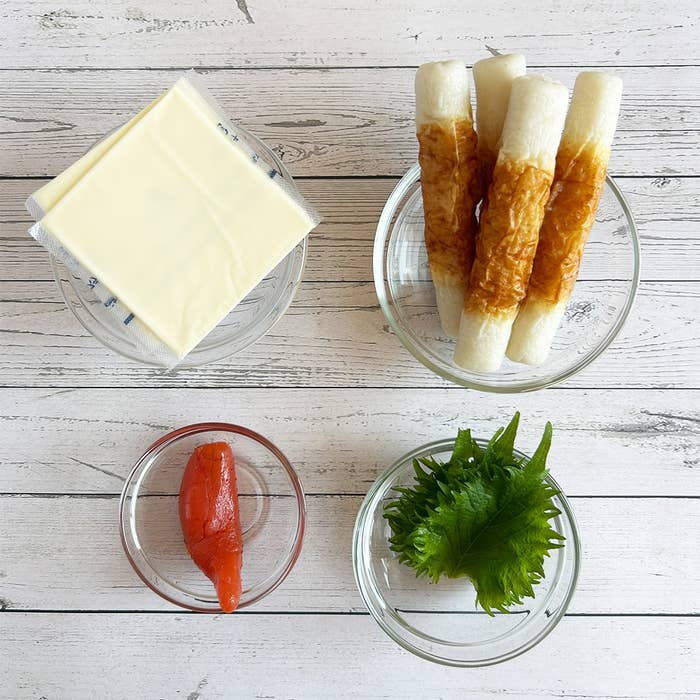 ちくわ、スライスチーズ、明太子、大葉がガラスの小皿に並べられた木製テーブルの上の一式。