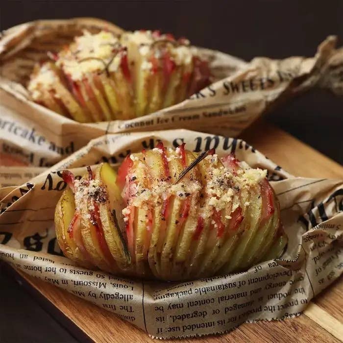 ジャガイモの薄切りグリル料理が新聞紙に包まれて盛り付けられている。