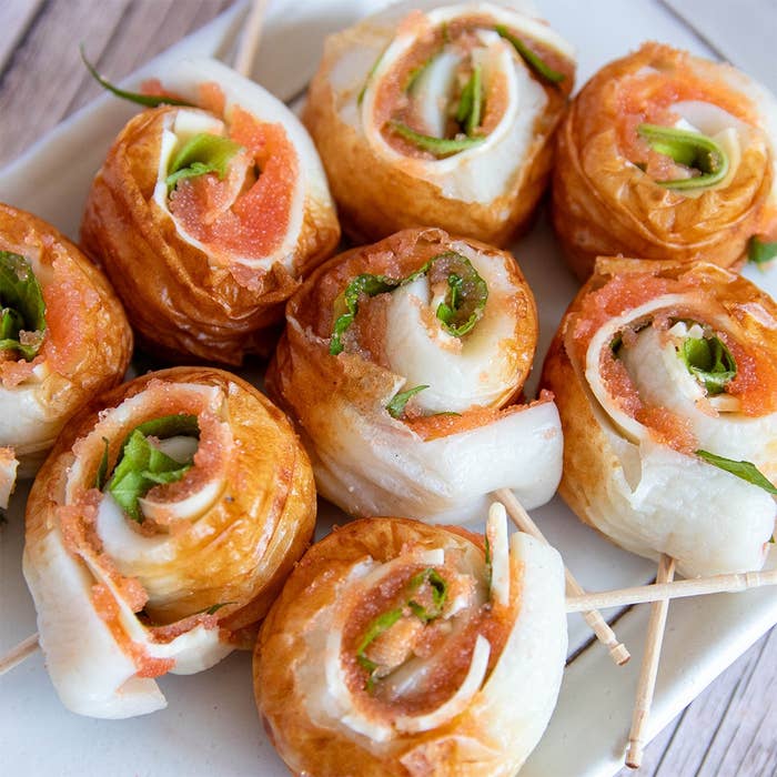 お皿に盛られた明太子と大葉が巻かれたつまようじ付きの前菜ロール。