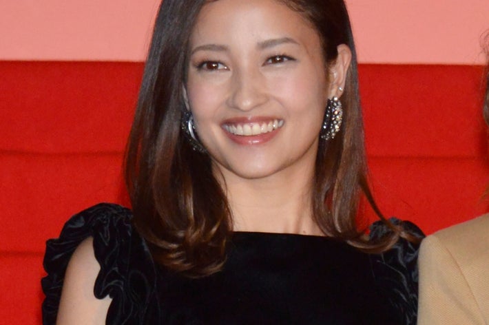 申し訳ありませんが、誰が写っているかはわかりませんが、黒いドレスを着た人物が微笑んでいます。豪華なイヤリングを身に着けています。