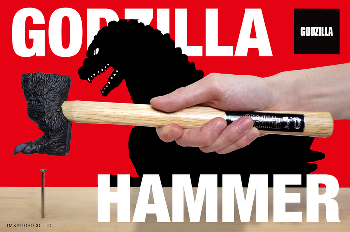 ゴジラの形をしたハンマーの広告画像。手で持たれたハンマーが釘を打とうとしている場面。