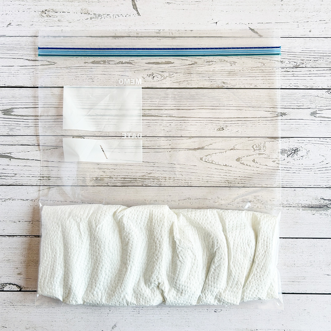 ジップロック袋に入った白い布が木製の床に置かれている。