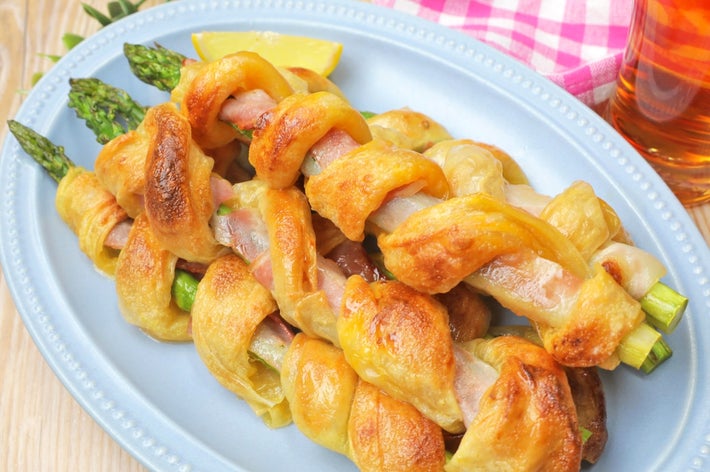 アスパラガスをベーコンとパイ生地で包んで焼いた料理が皿に盛られています。