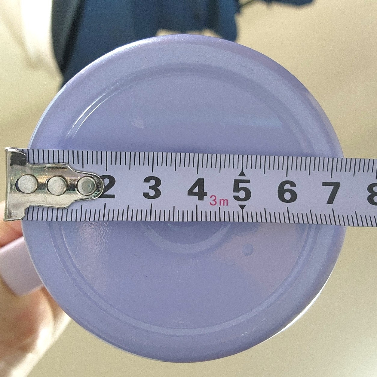 メジャーで直径を測定中の円形の物体。