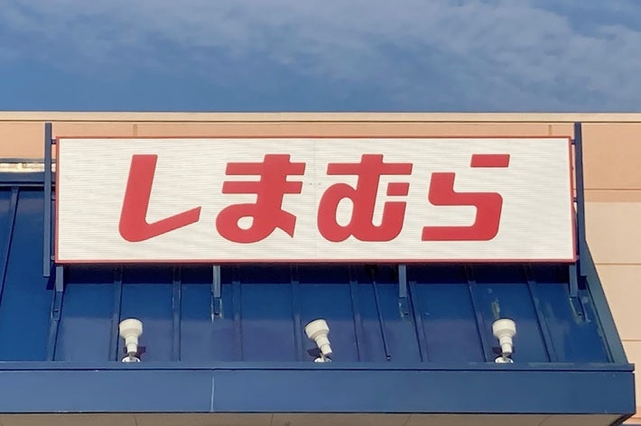 Sign with Japanese text &ldquo;しまむら&rdquo; mounted on a building facade under a blue sky