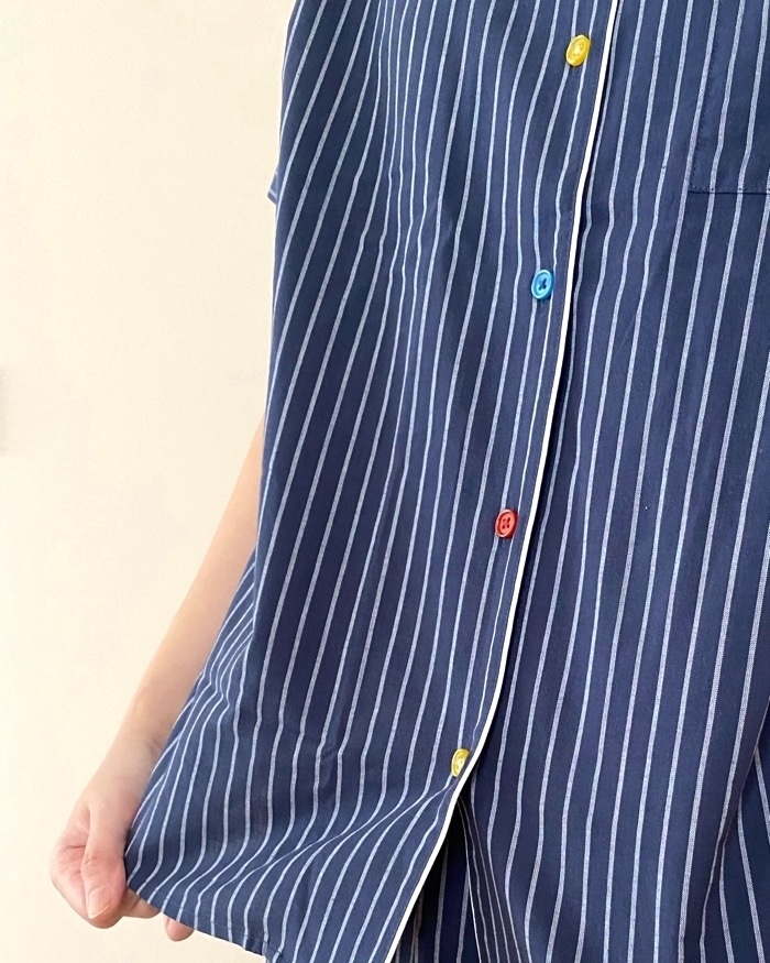 ストライプ柄のシャツを着た人物の上半身が写っています。カラフルなボタンが特徴です。