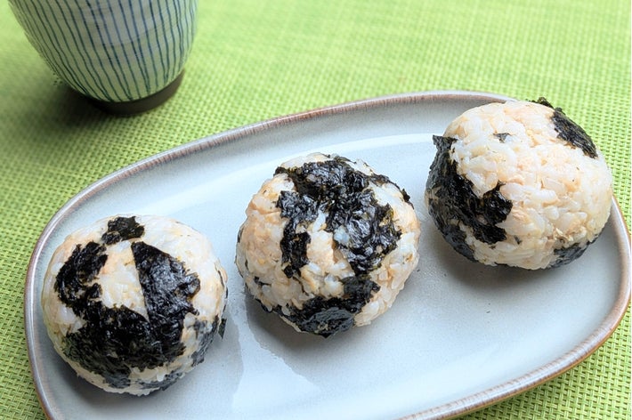 皿にのった3つの海苔おにぎりと、脇に置かれた湯のみ茶わん。文章はなし。