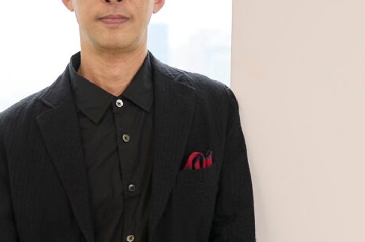 スーツ姿の男性が室内で立っている。落ち着いた雰囲気。