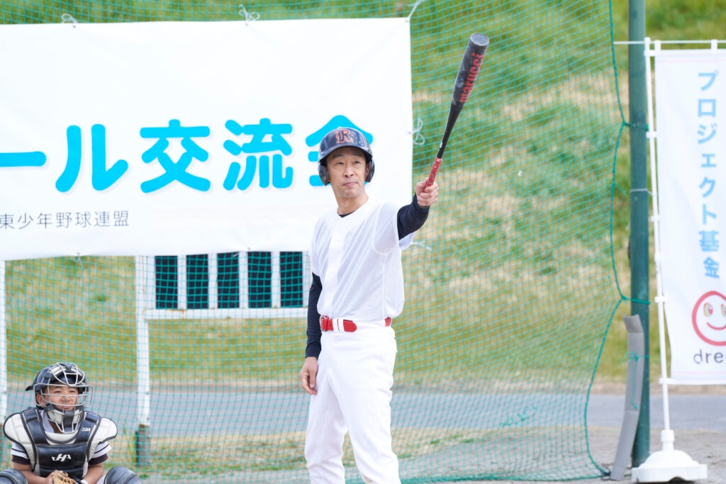 野球選手がバッターボックスに立ってバットを構えている。後ろにキャッチャーとネットがある。