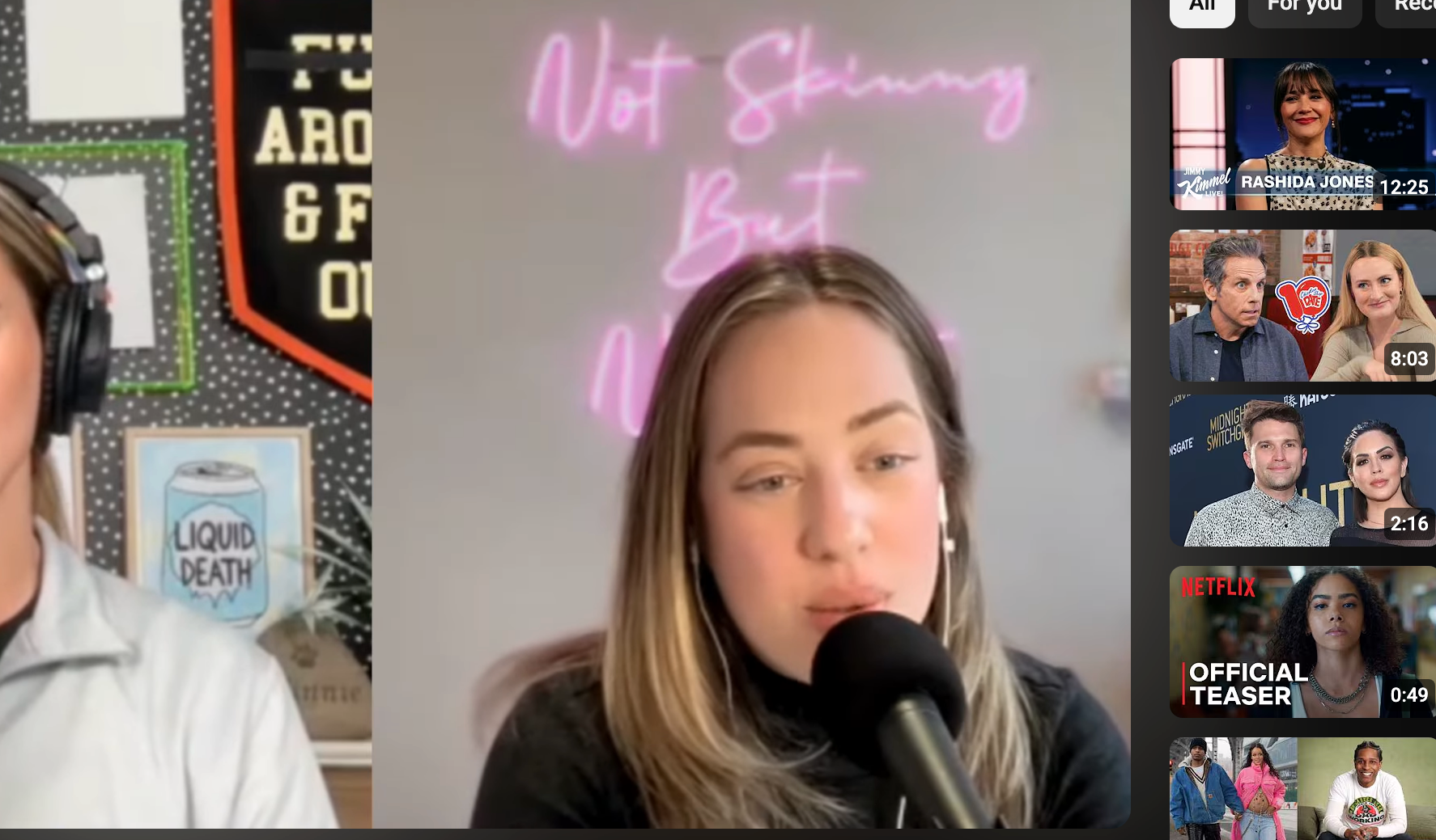 Kylie Kelce and Amanda Hirsch speaking into microphones during a podcast video on YouTube titled "Not Skinny But Not Fat"