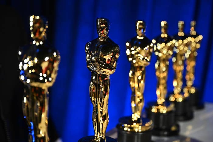 Golden statuettes lined up against a blue curtain, commonly known as awards given in the film industry