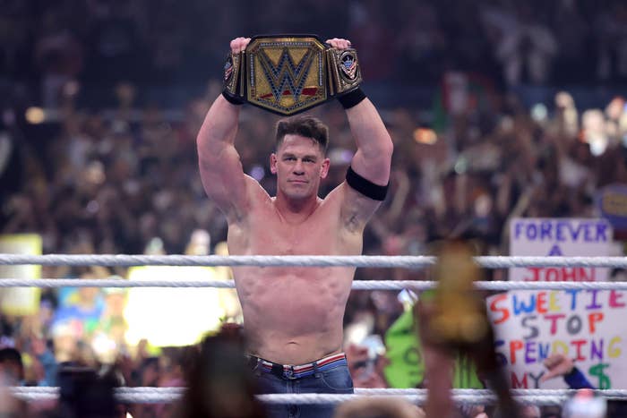 Wrestler holding a championship belt triumphantly in a crowded arena, wearing wrestling gear. 팬들 환호