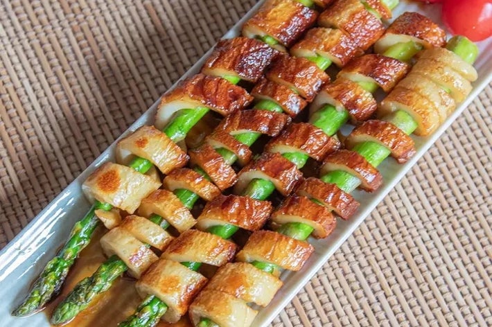 アスパラガスとちくわの串焼きが皿に盛られている。隣にミニトマトが添えられている。