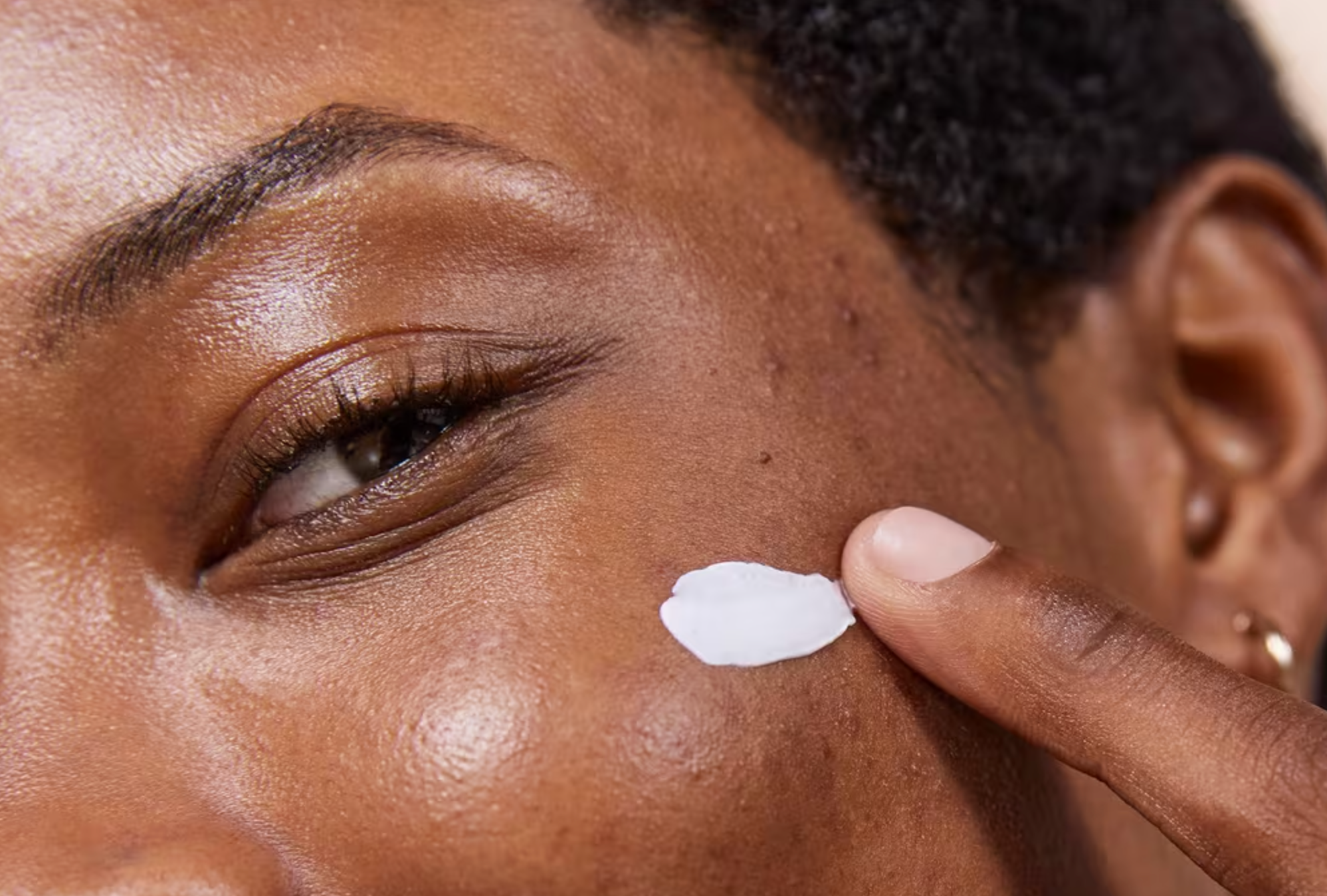 Person applying pick  to their cheek, close-up. Skin appears creaseless  and healthy