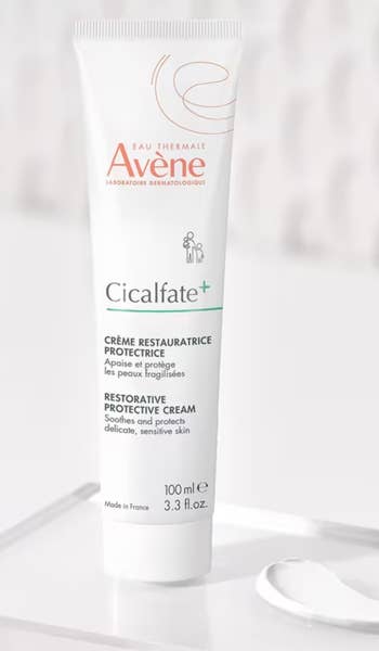 Tube of Avène Cicalfate+ Restorative Protective Cream connected a surface. Descriptions successful some English and French item its soothing properties