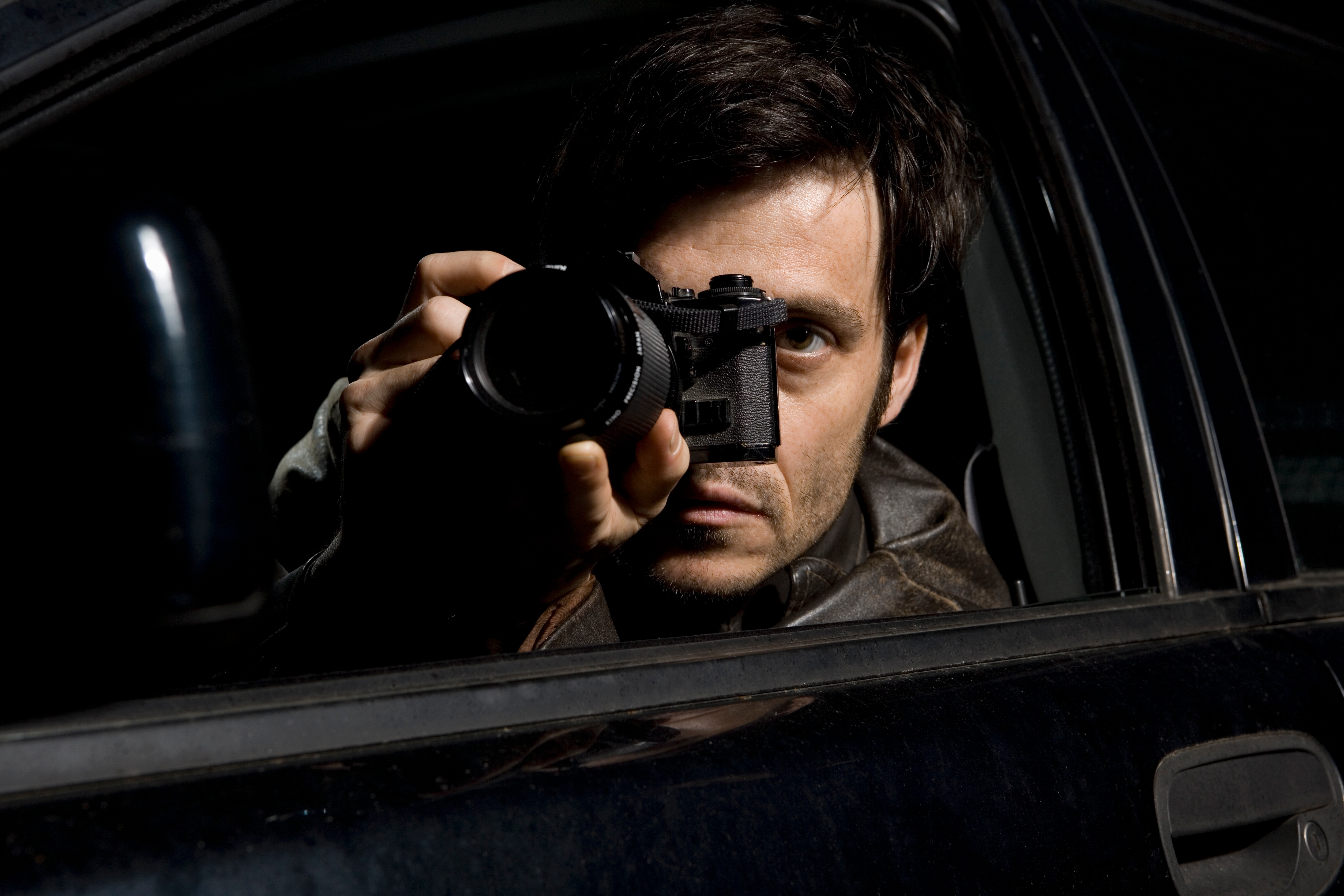 Person in a car taking a photo with a camera, partially obscured by shadow. They appear to be capturing something outside the vehicle