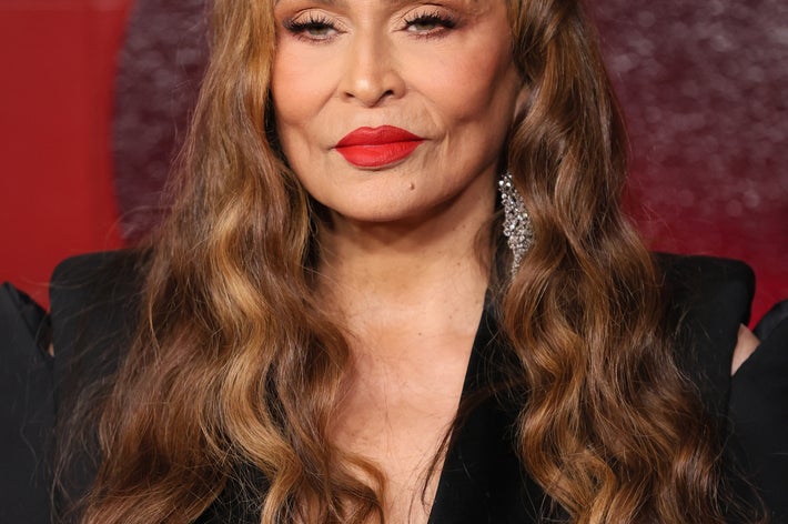 Tina Knowles with long wavy hair and elegant black formal attire poses with silver earrings