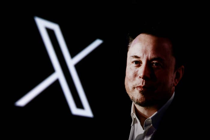 Prominent figure stands next to a stylized "X" on a dark background, wearing a formal suit