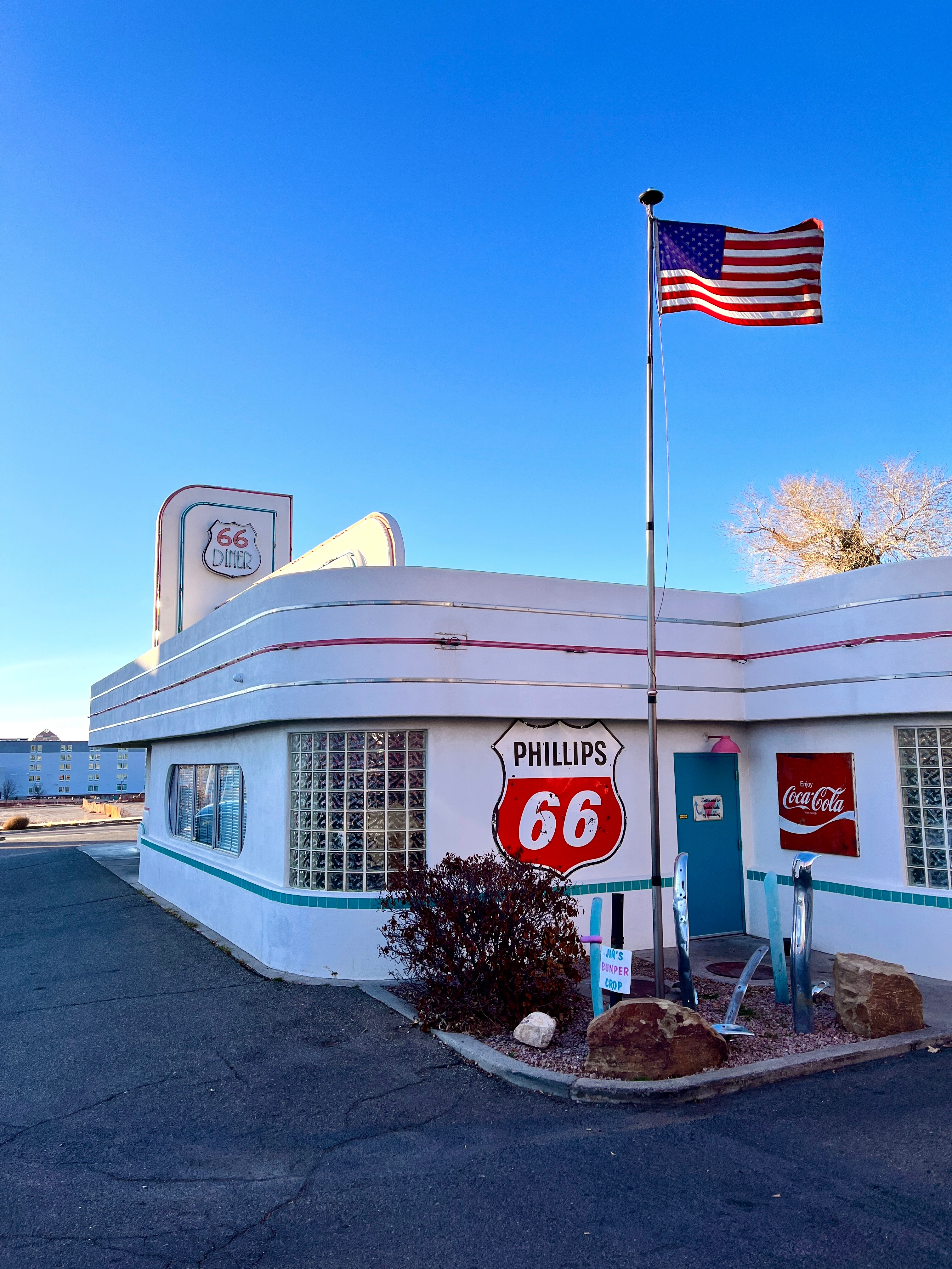 Route 66 diner with vintage signage, flag flying high, and classic pumps, evokes retro American road trip nostalgia