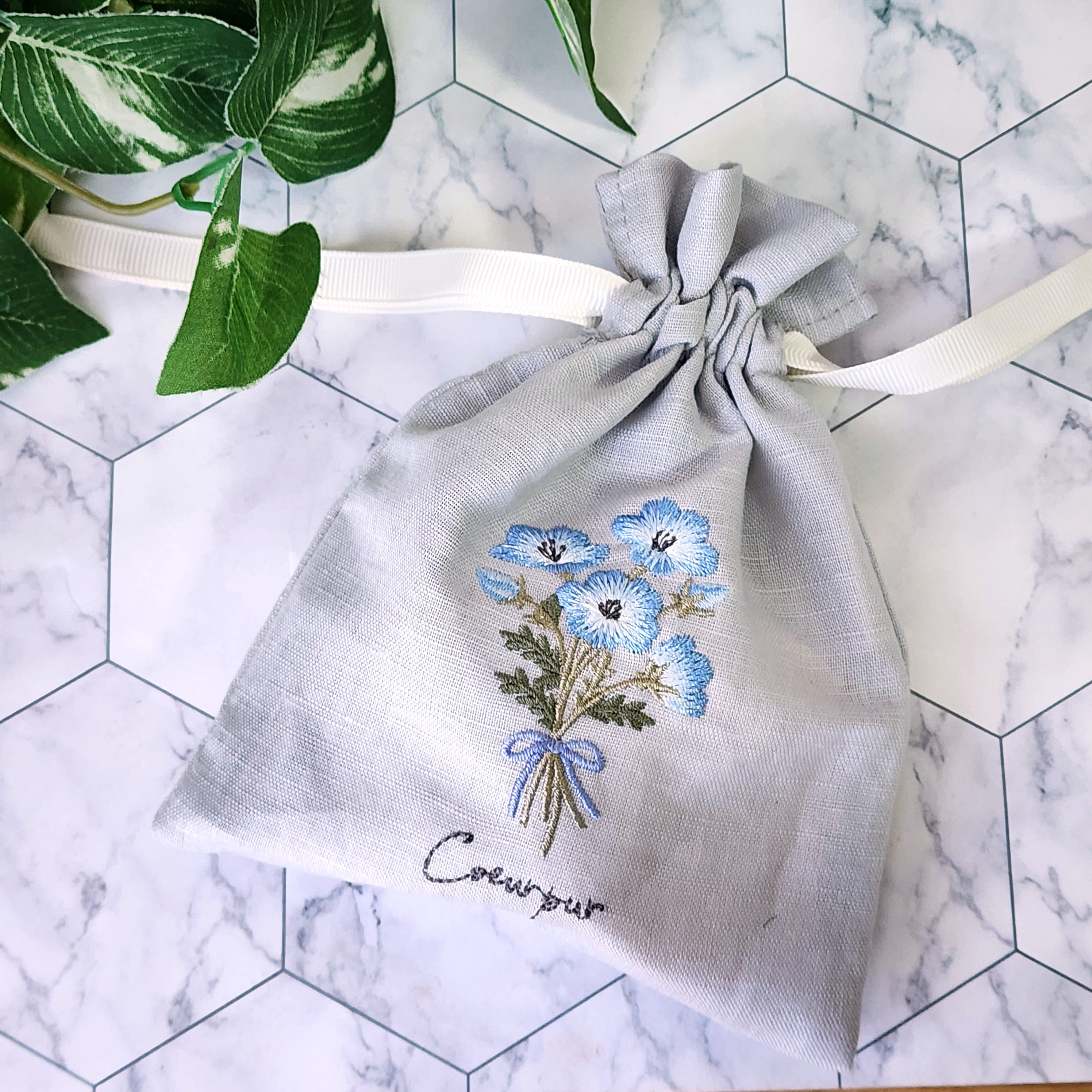 花の刺繍が入った束ねられた布製の巾着袋が置かれているイメージ。