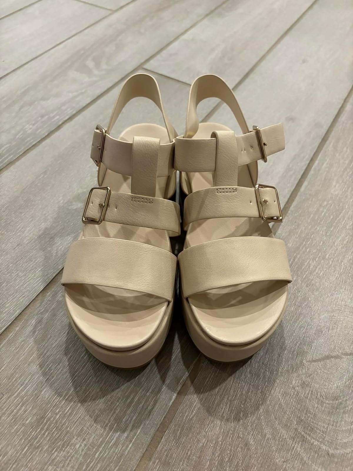 reviewer's brace  of beige level    sandals with straps and metallic  buckles