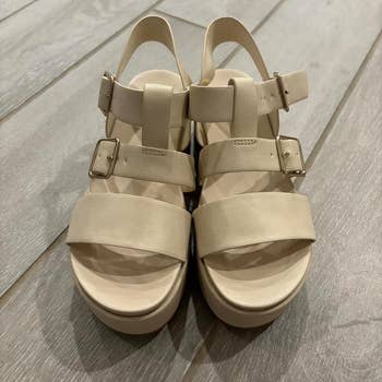 reviewer's brace of beige level sandals with straps and metallic buckles