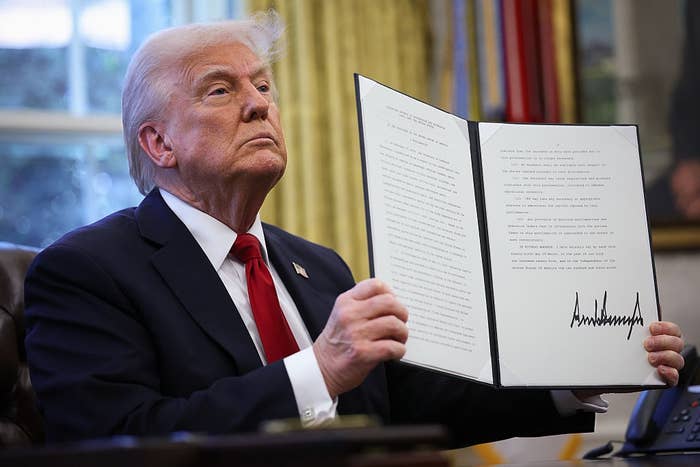 A person holds an open folder displaying a signed document in a formal setting