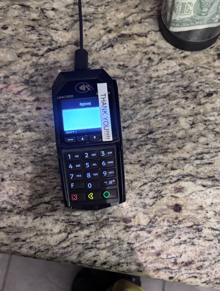 Card reader on counter displays &quot;Approved&quot; with a &quot;Thank You!&quot; sticker next to the screen