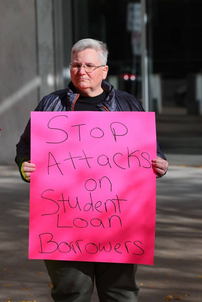 Person holding a sign that reads, "Stop Attacks on Student Loan Borrowers," during a protest