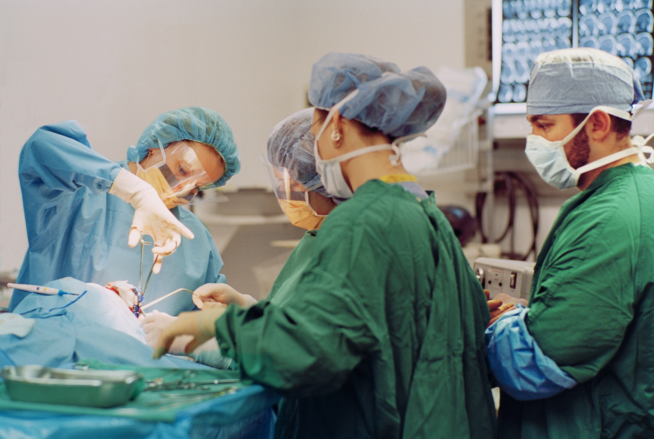 Medical team in surgical gowns and masks performing a procedure in an operating room