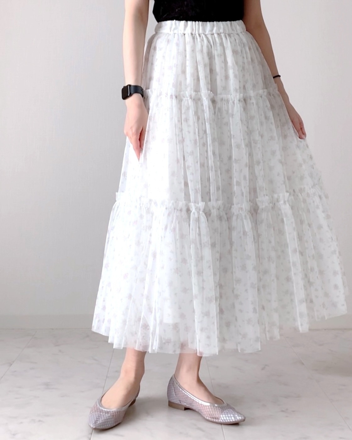 フローラル柄のティアードスカートを履く人の全身ショット。デリケートなレースの質感が特徴的。