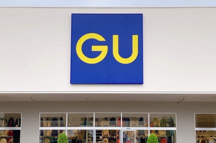 GU店舗の外観。大きな窓から服が見え、駐車車両が前面に停まっています。