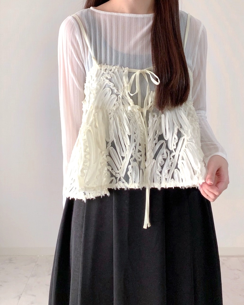 Person wearing a sheer long-sleeve top with a tie-front embroidered overlay and a black skirt