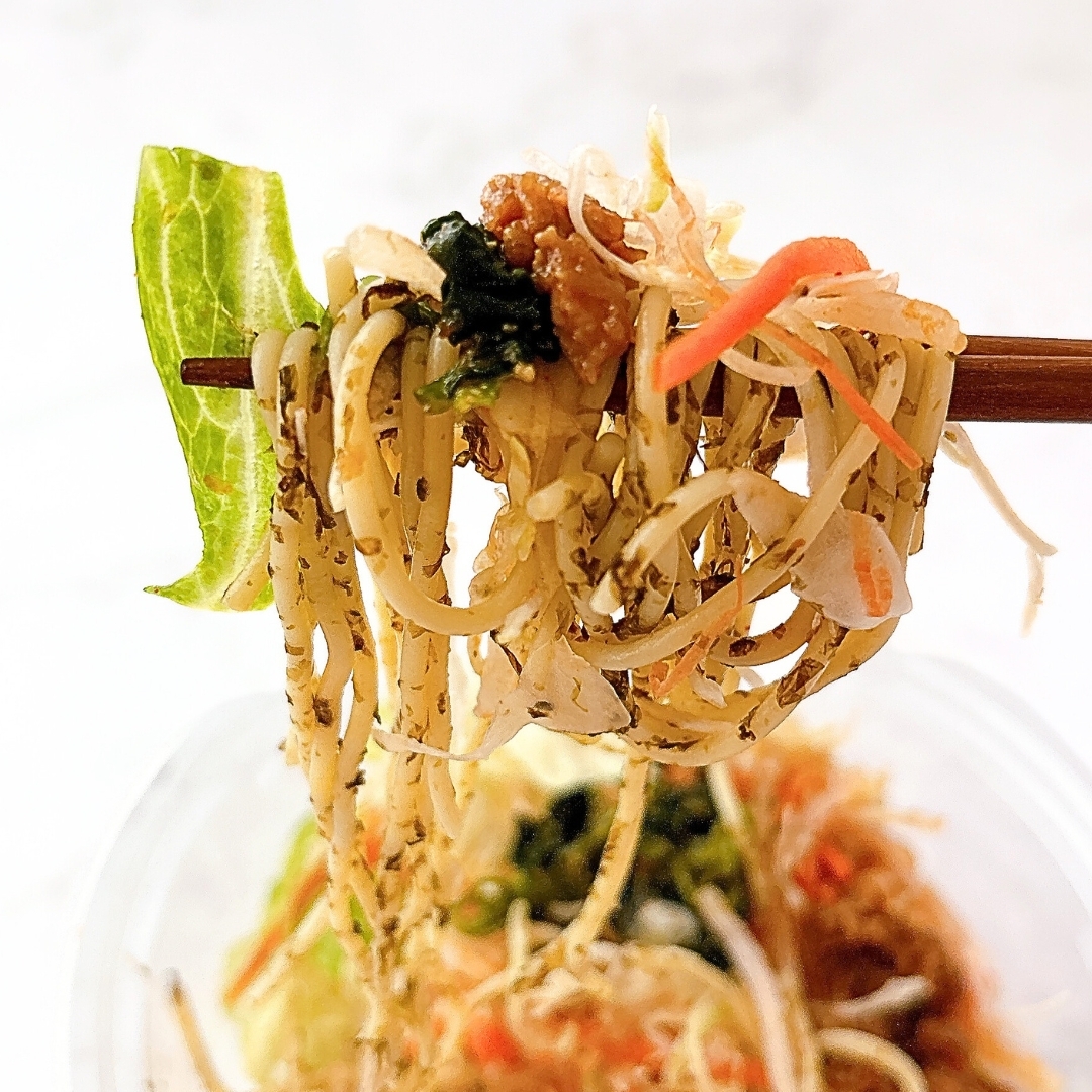 箸で持ち上げられたヌードルと野菜が見える食べ物のクローズアップ。