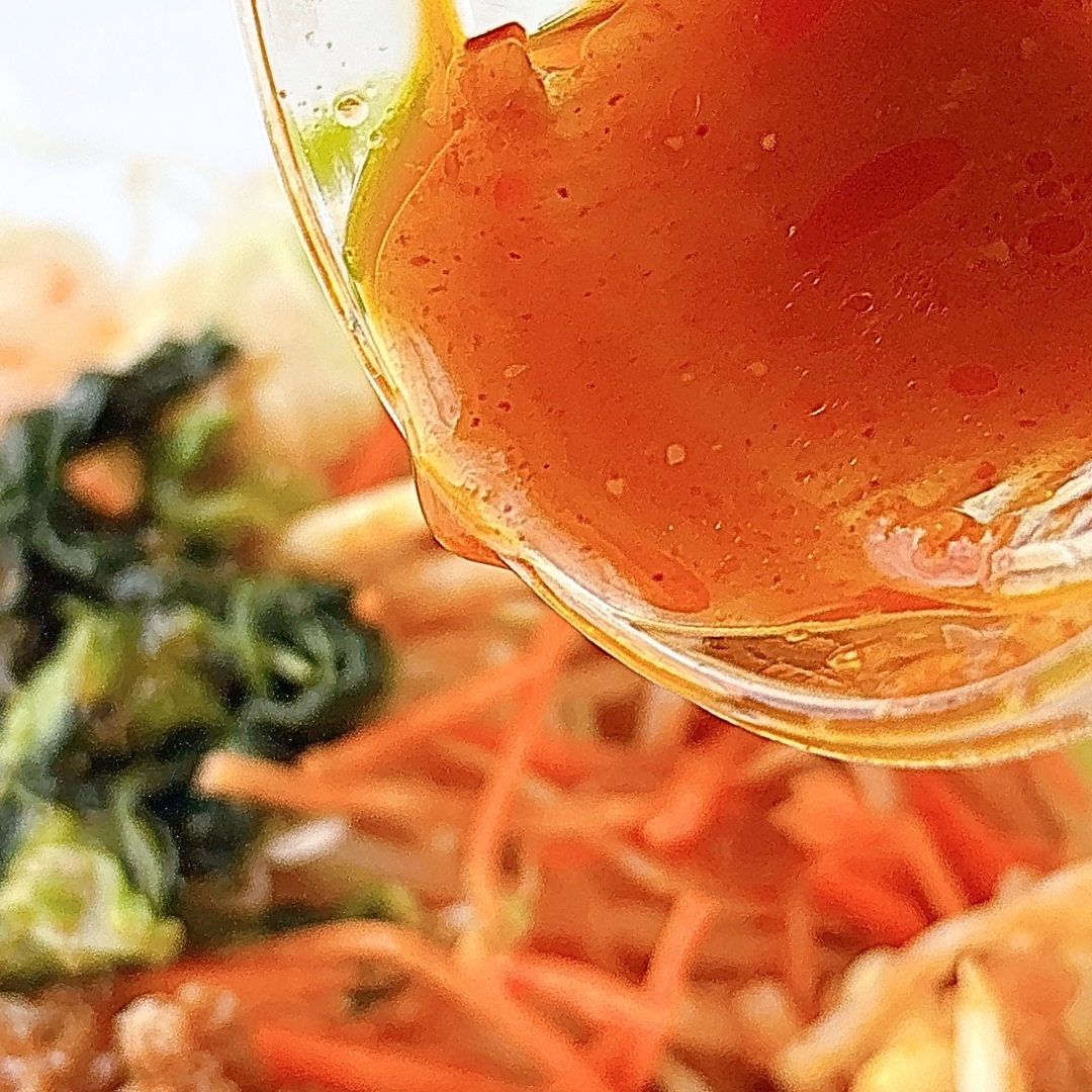 料理のアップ。ドレッシングが注がれているサラダには野菜が含まれています。