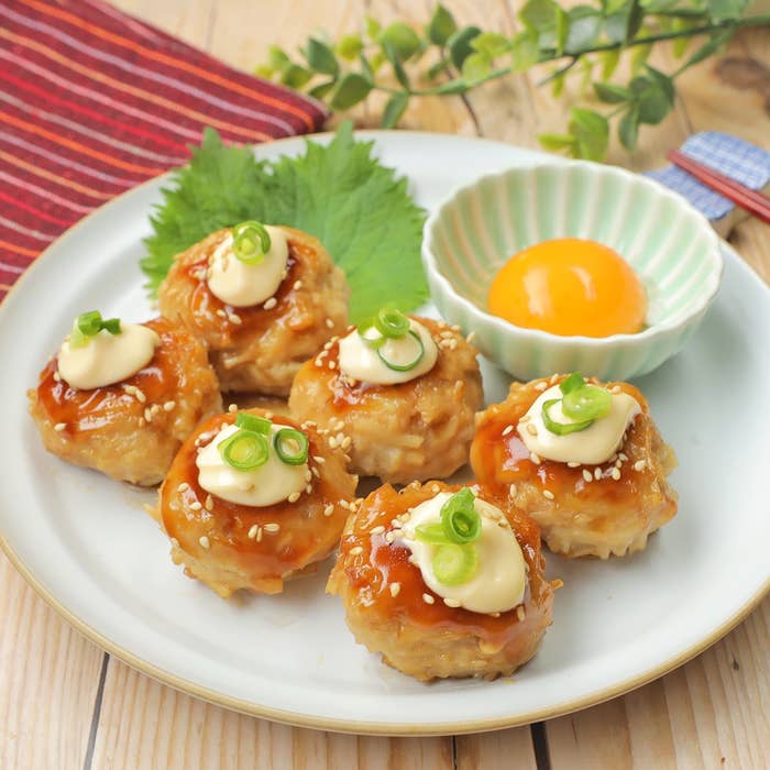 料理が皿に盛られ、上にマヨネーズと刻みネギが載っている。横に卵黄の入った小皿が添えられている。