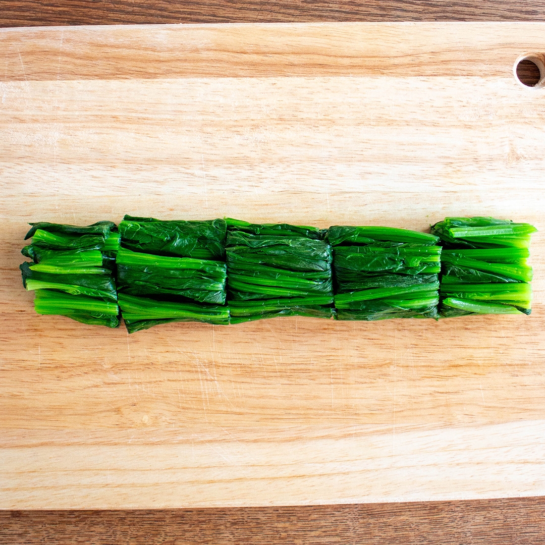 まな板に乗った緑色の野菜が数等分に切られています。