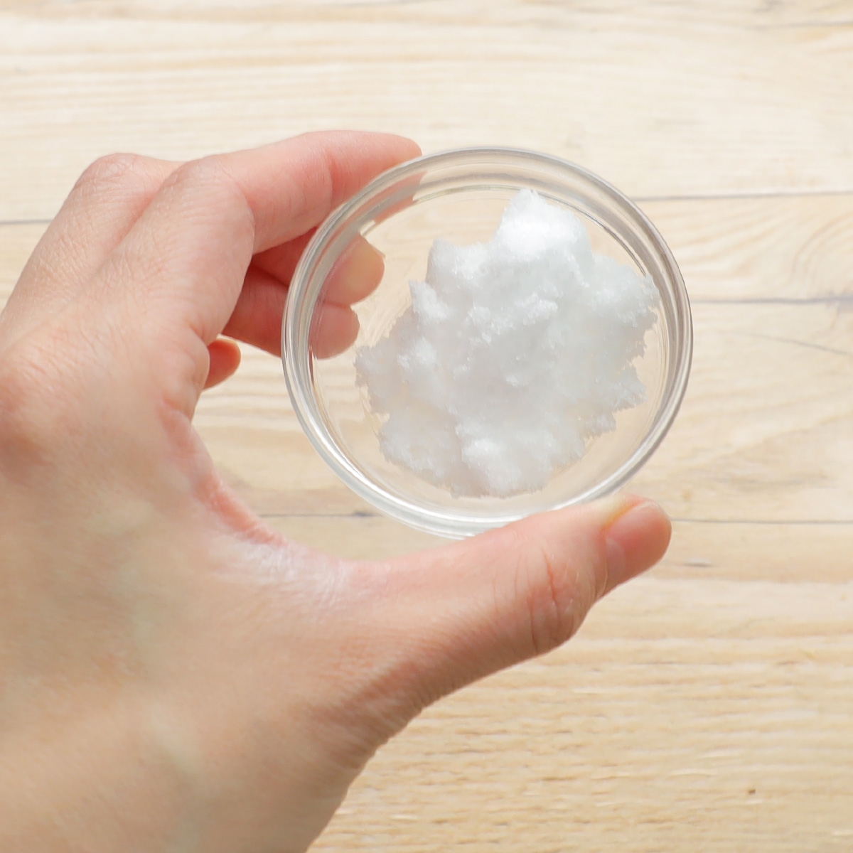 手に小さなガラス容器を持ち、白い固形の物体が入っている。直感的に自然の製品を示唆。