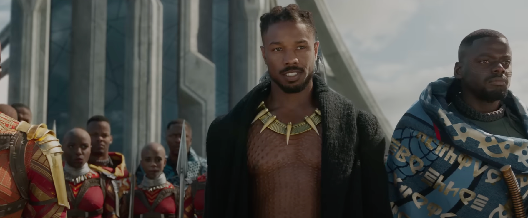 Chadwick Boseman as Killmonger in "Black Panther," wearing a black coat with a bare chest underneath