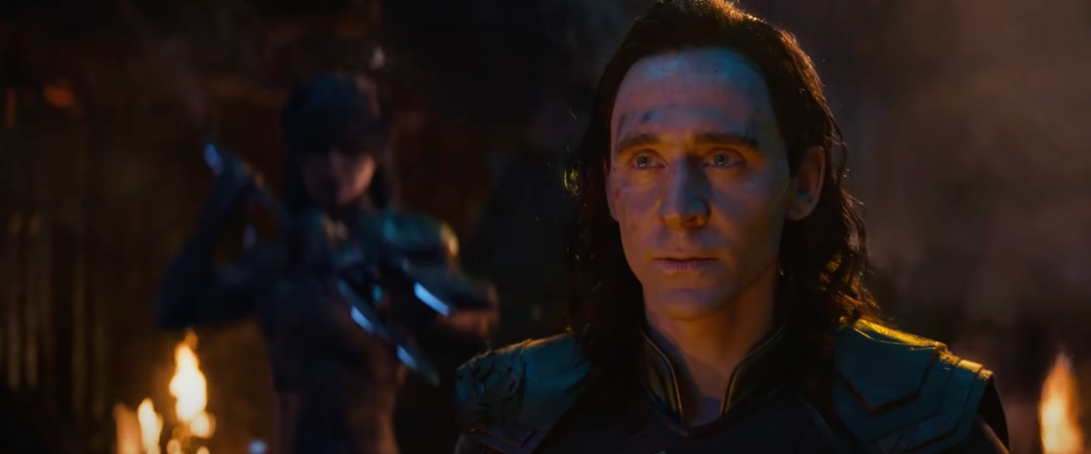 A character in dark armor stares solemnly ahead, with an out-of-focus figure in armor behind them