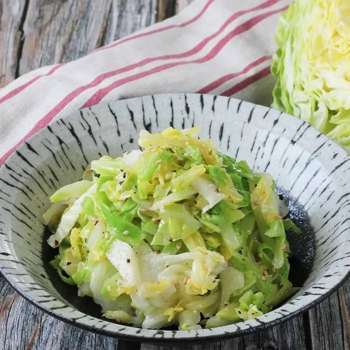 千切りキャベツが皿に盛られており、背後にキャベツの断面が見える。