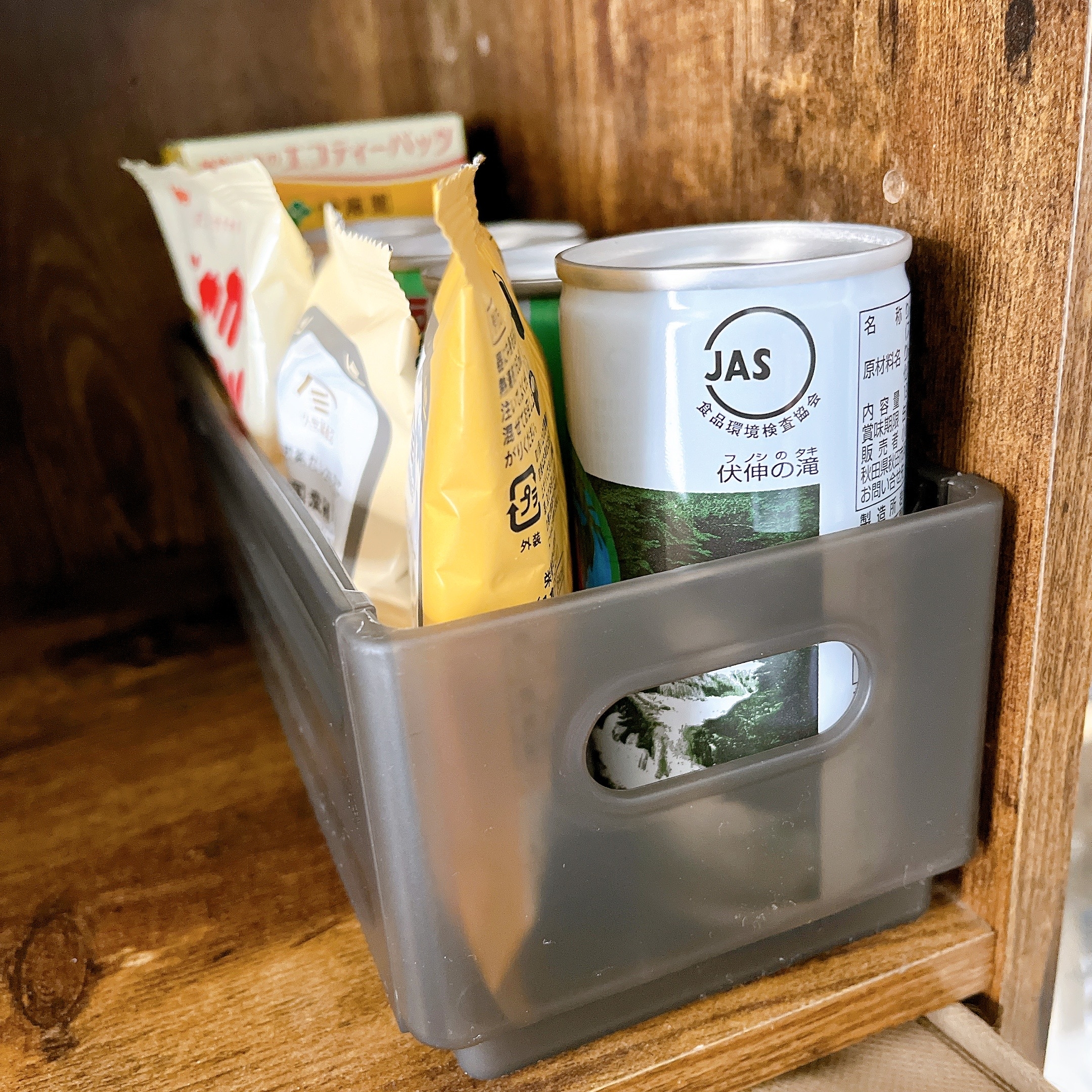棚に収納された缶と袋の食品がプラスチックケースに入っている。