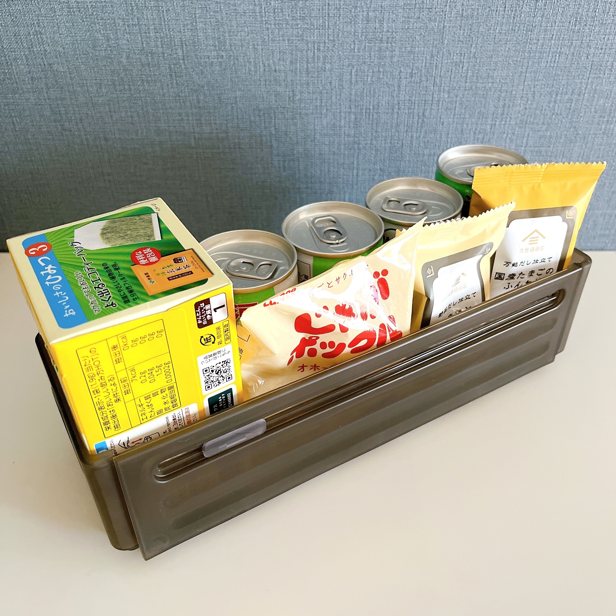 飲み物の缶、スナック、ティッシュが整理箱に収納されています。