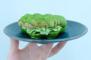 抹茶クリームが入ったドーナツが青い皿にのせられ、手に持たれています。