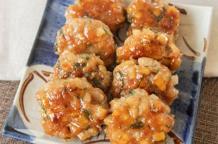 れんこん入り照り焼き豚つくねが皿に盛られ、照り焼きソースが絡まっている。