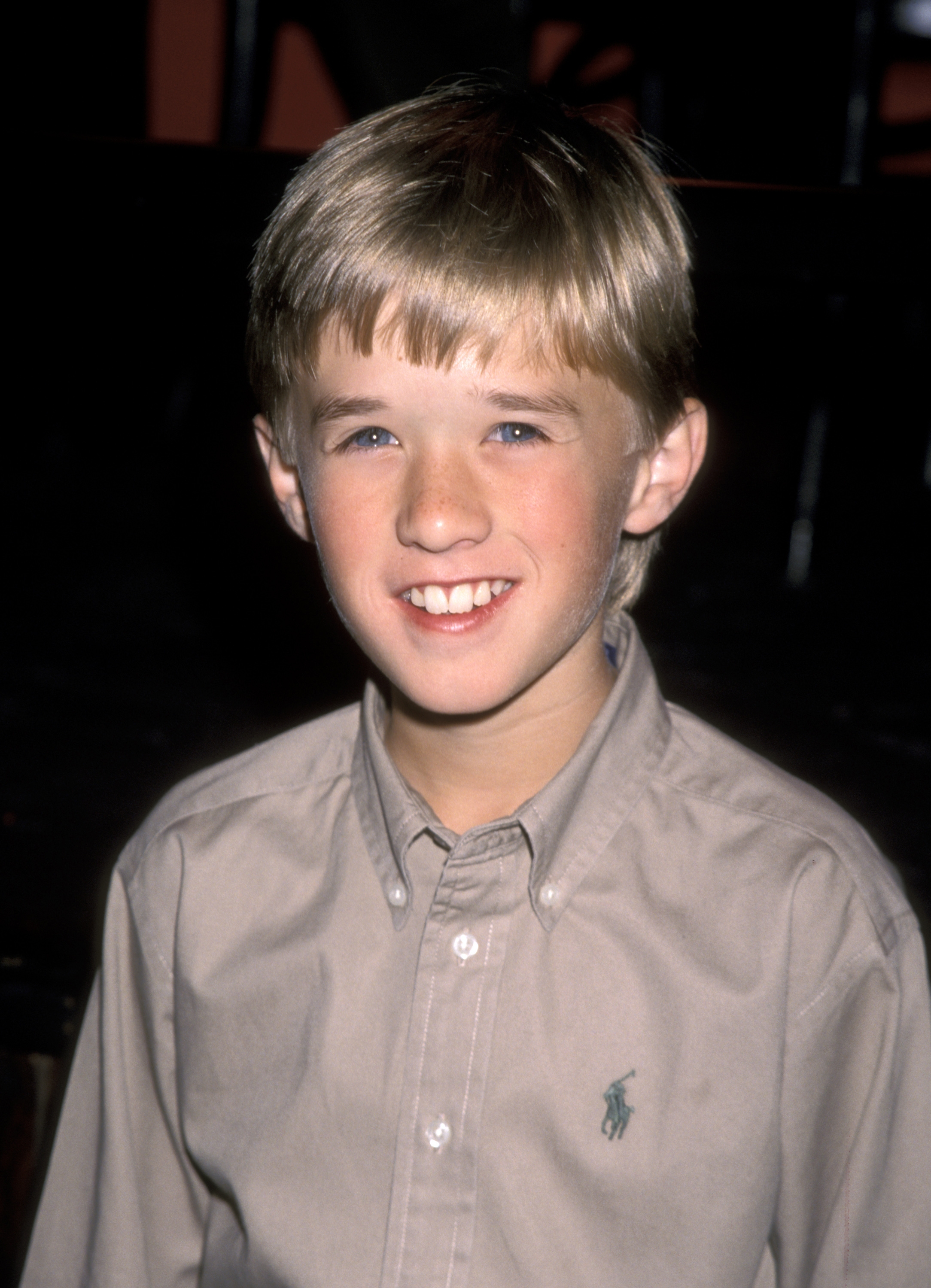 Young child smiling in a button-up shirt. Appears to be at an event