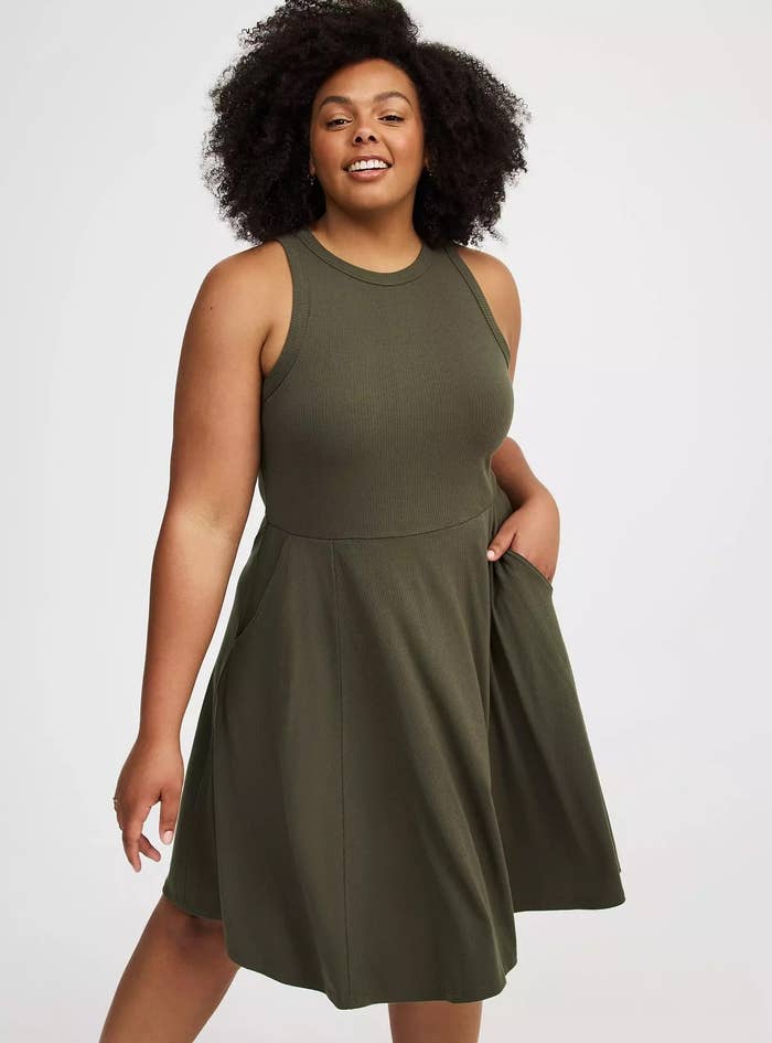 Person confidently modeling a sleeveless, knee-length formal  with pockets, suitable for casual wear
