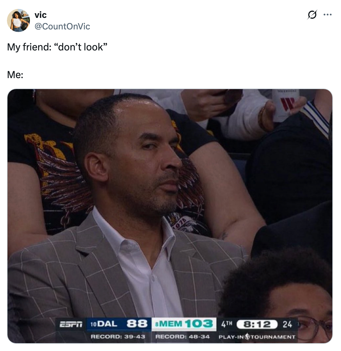 A person in a checked suit looks skeptically to the side at a basketball game. Scoreboard shows Dallas 88, Memphis 103, 4th quarter, 8:12 left
