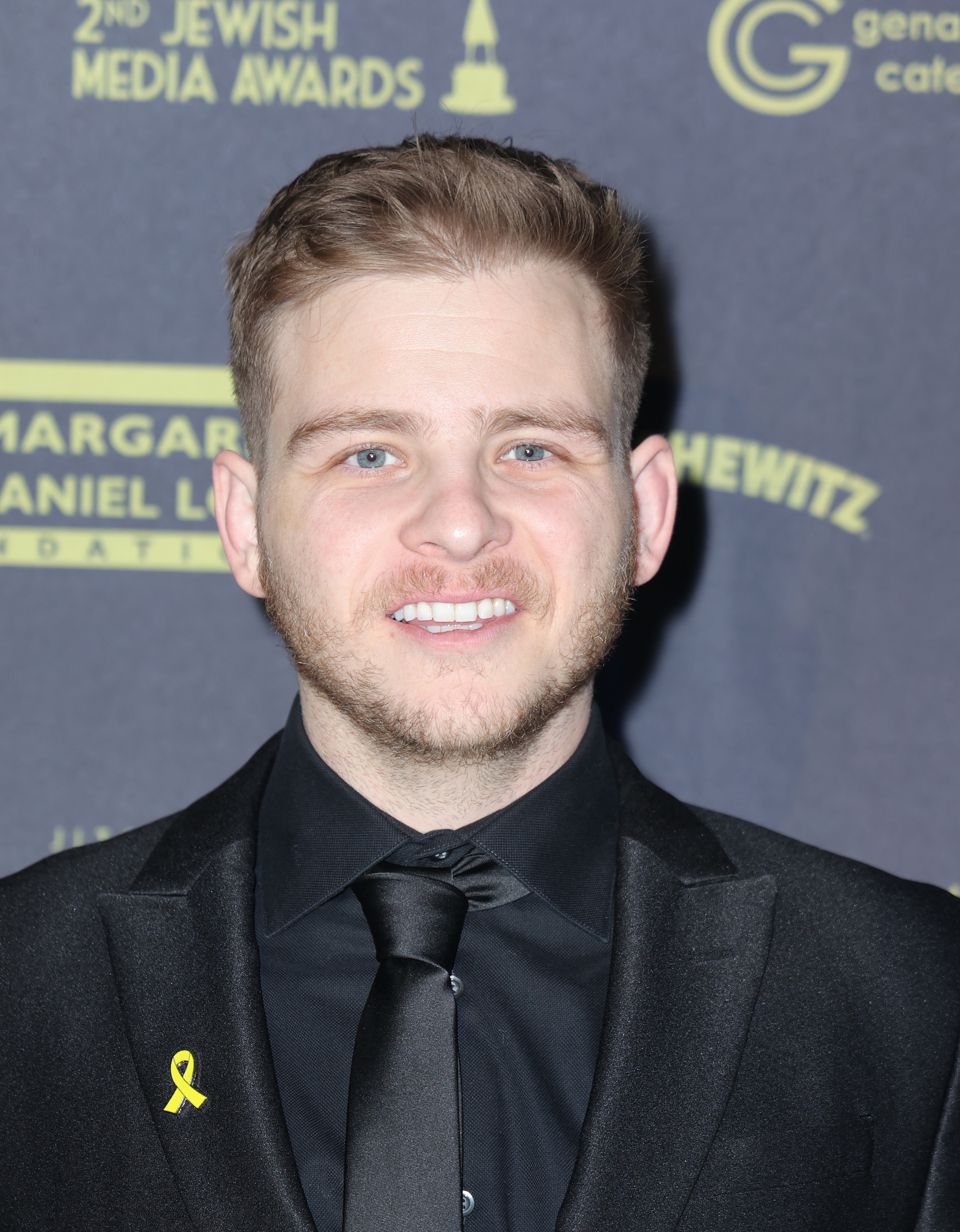 A person in a suit with a ribbon pin attends a formal event